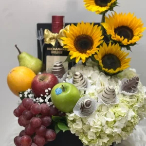 Caja con girasoles, ortensias, fresas con chocolate, frutas y botella de Buchana's