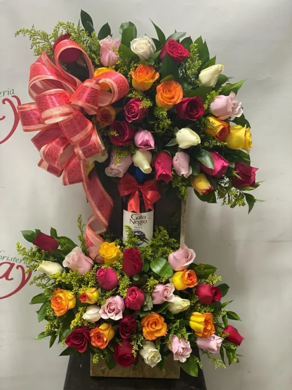 Arreglo floral de dos pisos con rosas surtidas y botella de vino gato negro.